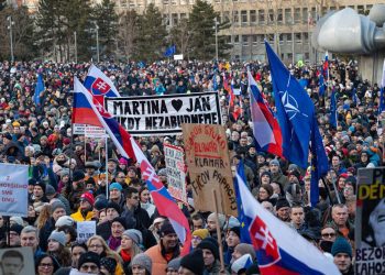 Účastníci s transparentmi a vlajkami počas spomienkového zhromaždenia k 7. výročiu vraždy Jána Kuciaka a Martiny Kušnírovej, ktoré spoločne organizujú Mier Ukrajine a Za slušné Slovensko na Námestí slobody v Bratislave. Bratislava, 21. február 2025. Foto: SITA/Jana Birošová