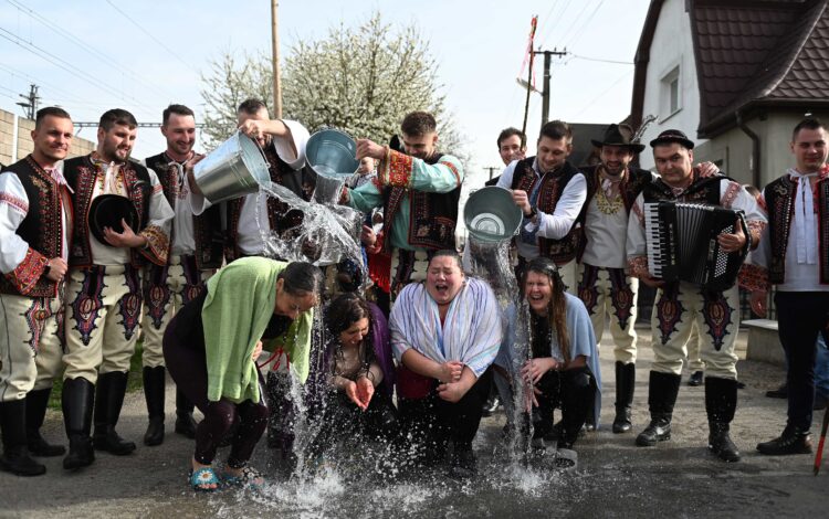 Chlapci v krojoch polievajú dievčatá počas tradičnej oblievačky a šibačky na Veľkonočný pondelok  Foto: SITA/Tomáš Somr