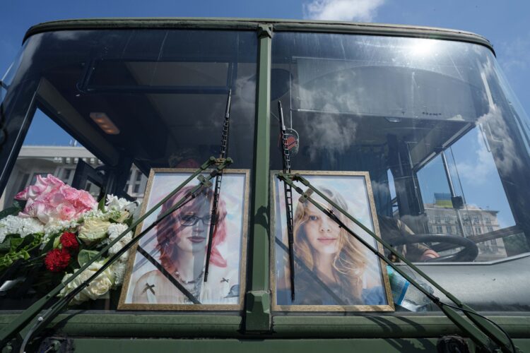 Portréty sestier Ľubavy a Viry Jakovlevových, ktoré začiatkom mája zahynuli pri ruskom raketovom útoku na obytnú budovu, sú umiestnené za čelným sklom autobusu počas ich pohrebu v Kyjeve. Pohreb sa konal v utorok 19. mája 2026. FOTO: SITA/AP Photo/Evgeniy Maloletka