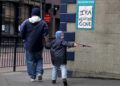 Chlapec s puškou na hraní prochází v roce 2005 v Belfastu kolem plakátku s nápisem "IRA beze zbraní". Irská republikánská armáda (IRA) tehdy zcela odzbrojila a zbavila se zbraní, jimiž po 30 let bojovala za odtržení Severního Irska od Británie. Foto: ČTK /